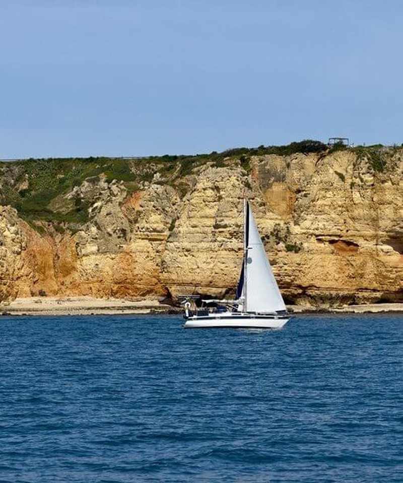 Sailing yacht off the Algarve cliff coast