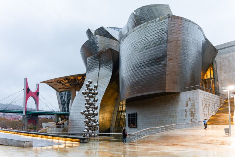 Guggenheim-Museum Bilbao mit Edelstahlkugel-Skulptur und roter La-Salve-Brücke am Fluss Nervión