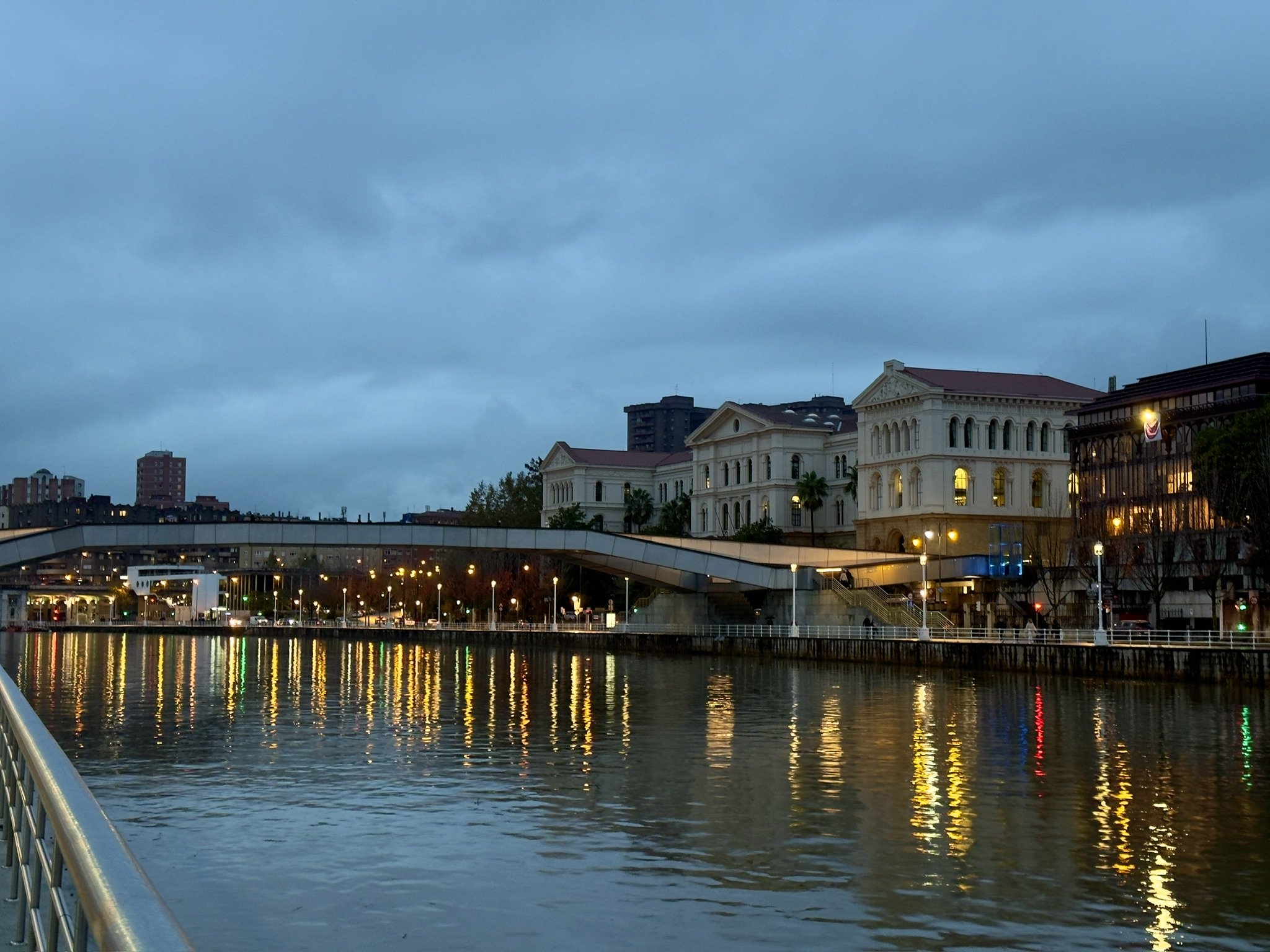 Uferpromenade am Fluss Nervión in Bilbao in der Dämmerung mit spiegelnden Lichtern