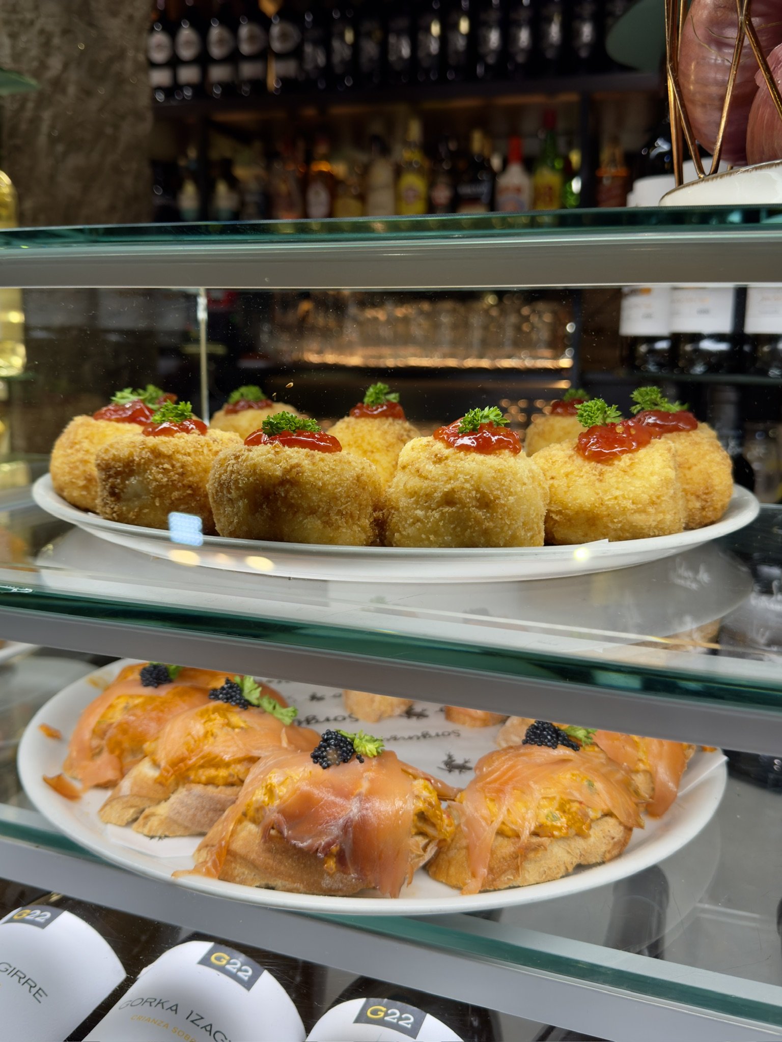 Pintxos mit Kroketten und Lachs in einer Bar-Vitrine in Bilbao