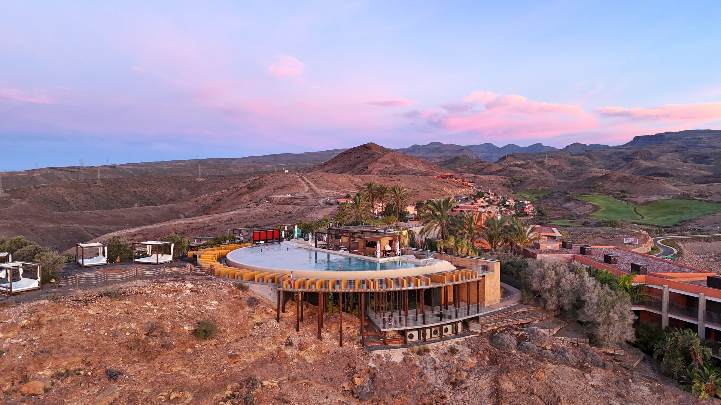 Infinity pool of a hotel complex at sunset over the mountains in southern Gran Canaria, drone shot