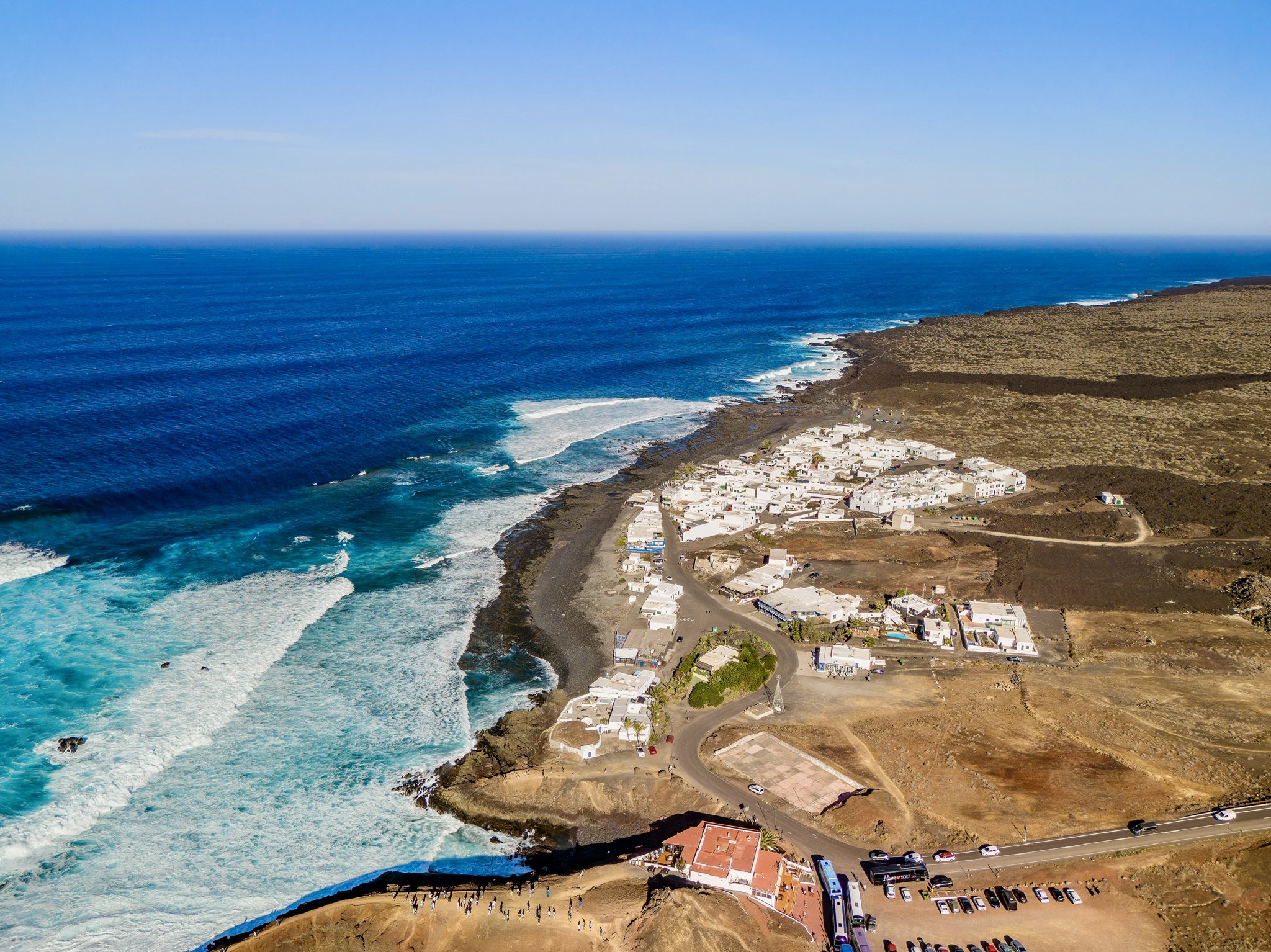 Weiße Küstensiedlung zwischen Lavafeldern und Atlantik auf Lanzarote aus der Luft