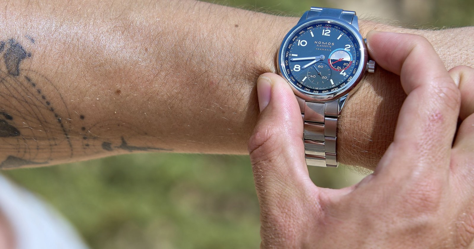 Hands close a NOMOS Glashütte wristwatch on the wrist
